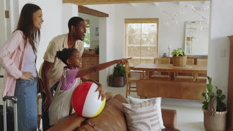 diverse family enjoying vacation at home, pointing excitedly while holding beach ball