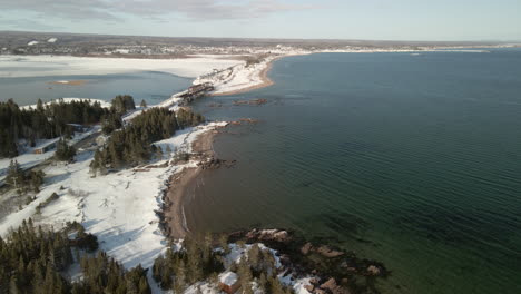 Drone-flight-over-the-ocean-in-winter-with-snow-in-Chandler,-Quebec,-Canada