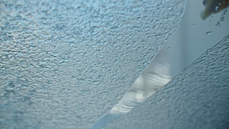 close up shot of scraping a car window, removing ice