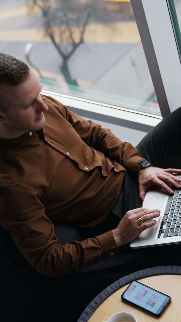 Attractive man using laptop in co-working space. Vertical video