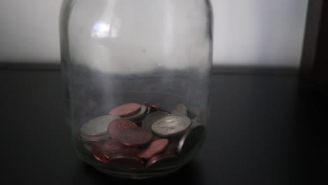 poner monedas en un frasco de ahorros