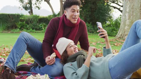 video de una pareja biracial pasando calorosamente tiempo en el jardín y usando un teléfono inteligente