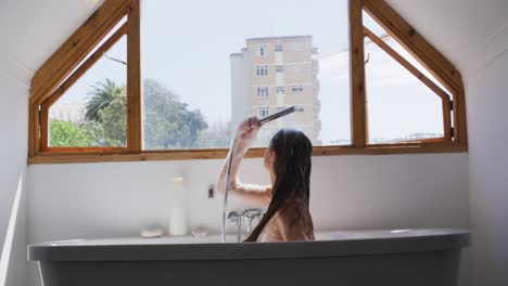 mujer duchándose en la bañera en el baño