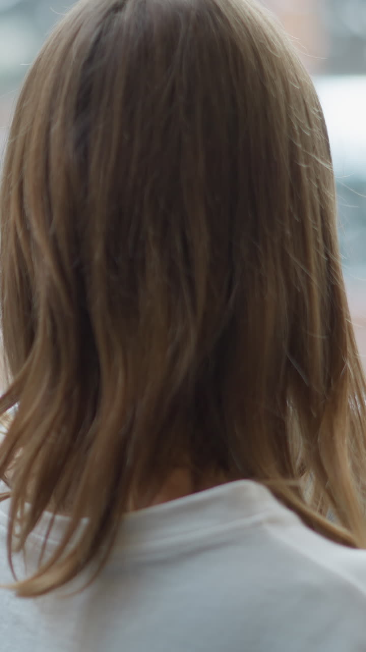 유리 패널과 흐릿한 자연 빛 반사를 통해 현대적인 도시 환경을 강조하는 부드러운 조명으로 움직이는 엘리베이터 내부의 젊은 여성의 뒷면