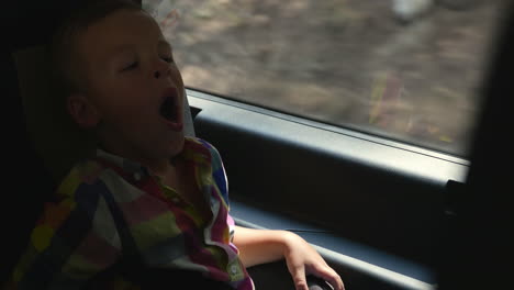 little child traveling by car and yawning