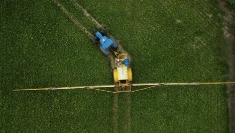 Drohnenaufnahmen-Direkt-über-Einem-Traktor-Mit-Einer-Gezogenen-Feldspritze,-Die-Auf-Einem-Feld-Nach-Links-Abbiegt