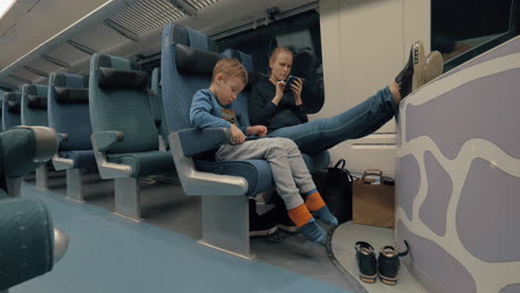madre y hijo usando electrónica durante el viaje en tren