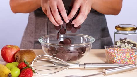 hands mixing chocolate with fruits and sprinkles