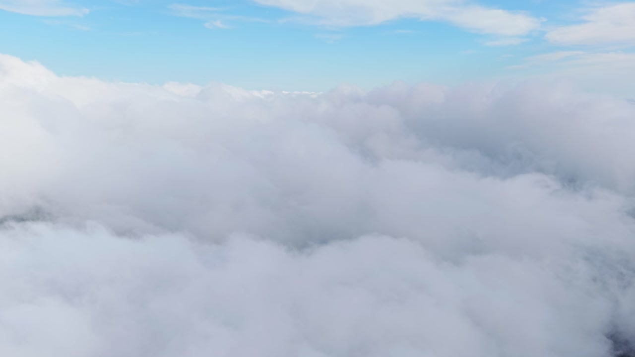 Large cloud cover with a sky above, seen from an aerial perspective with the blue sky above