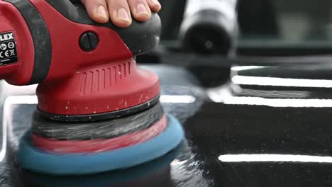 polishing black shinning surface of vehicle with industrial tool, close up view