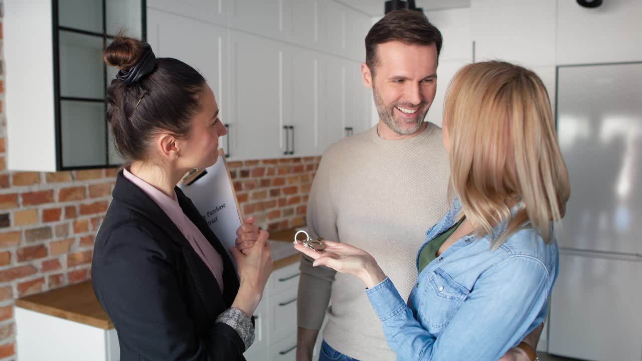 Video eines selbstbewussten, lächelnden Immobilienmaklers, der einem Paar die Hausschlüssel übergibt