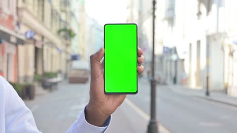 african man holding smartphone with green chroma screen