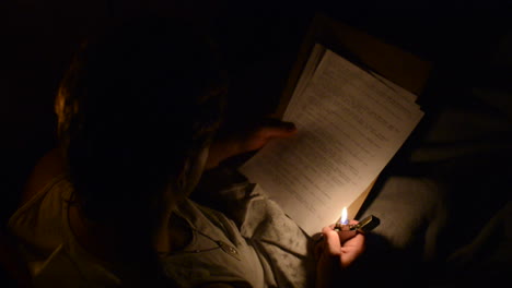 young soldier lighting a lighter to read a letter while in bed