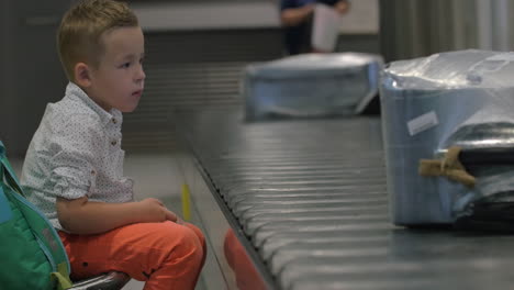 Niño-Esperando-En-La-Zona-De-Recogida-De-Equipaje.