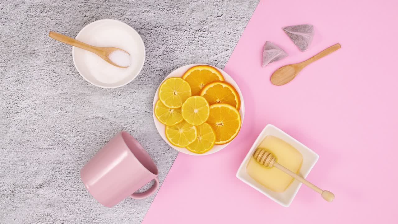 Pink cup, sliced lemons and orange and honey and sugar move. Stop motion