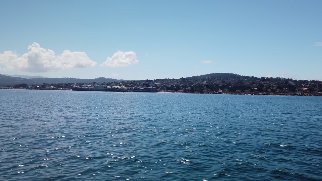 gimbal amplia toma panorámica acercándose a monterey, california desde un barco en el océano