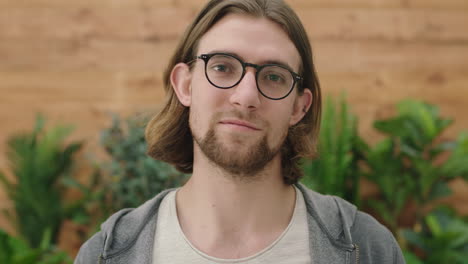 portrait of cute young geeky man wearing glasses looking at camera serious pensive in garden background