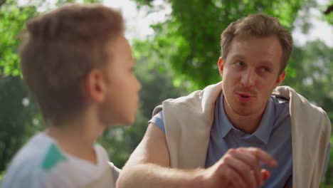 Smiling-father-talking-with-son-on-nature-close-up.-Happy-family-rest-concept.