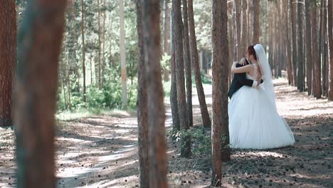 Braut-Im-Hochzeitskleid-Springt-Dem-Bräutigam-In-Die-Hände,-Die-Handlung-Spielt-Sich-Im-Wald-In-Zeitlupe-Ab