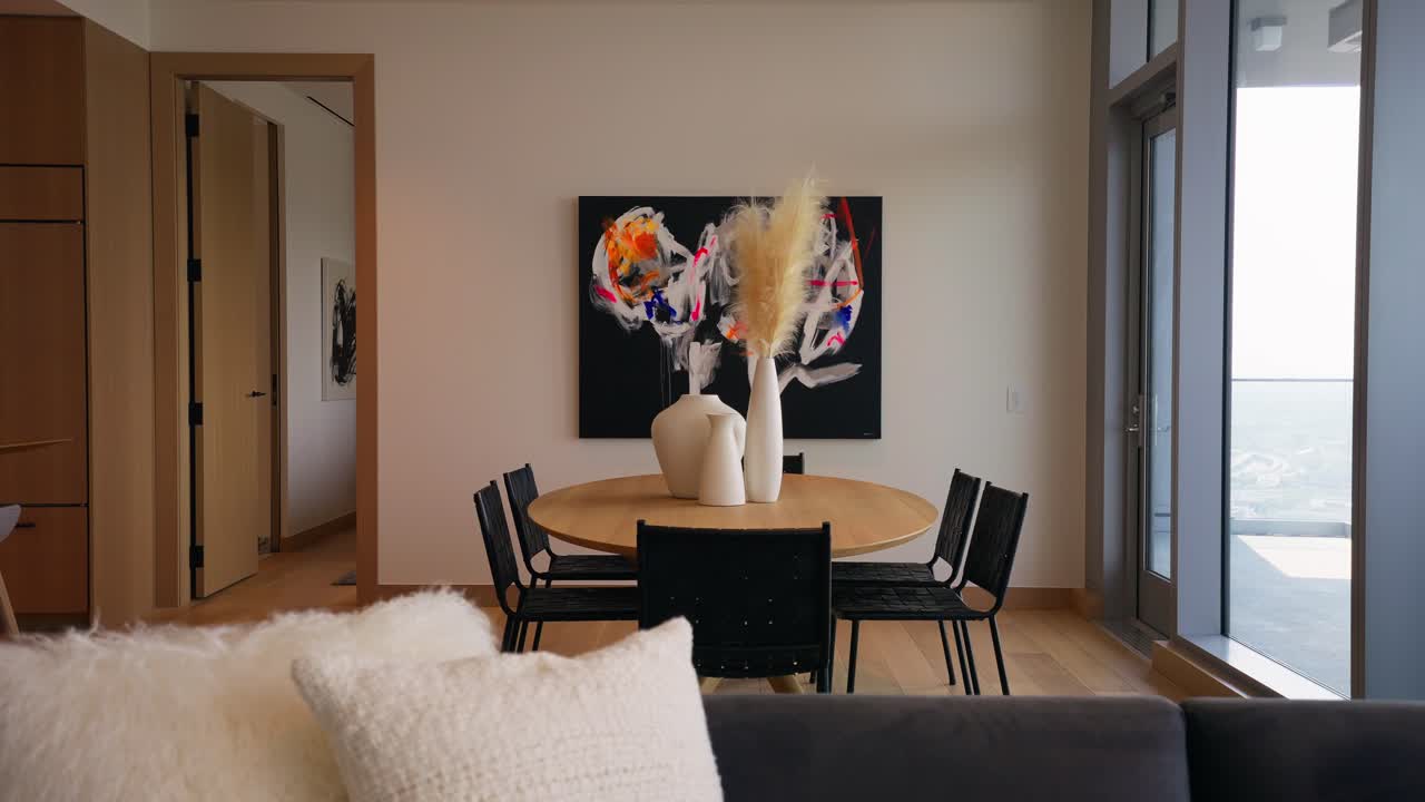 fotografía panorámica de una sala de comedor moderna con una mesa de madera rodeada de sillas negras, con una obra de arte cautivadora expuesta en el fondo