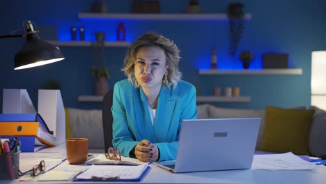 una donna che lavora in ufficio a casa che guarda la telecamera arrabbiata.