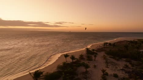 drone orbiting private island in northeast madagascar during golden hour reveals oceanfront huts, swaying palm trees, and a glowing sea horizon bathed in soft sunset light