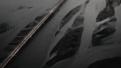 aerial orbit: bridge leading over glacial river bed in iceland