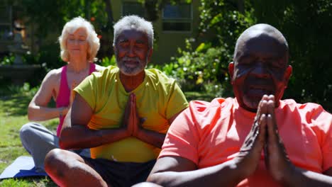 Front-view-of-active-mixed-race-senior-people-performing-yoga-in-the-garden-of-nursing-home-4k