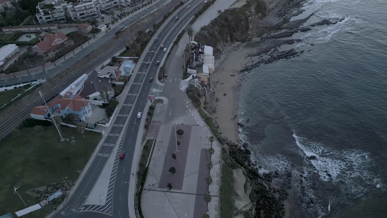 Vista aérea del frente marítimo durante un amanecer espectacular, con olas rompiendo contra las rocas en Lisboa.
