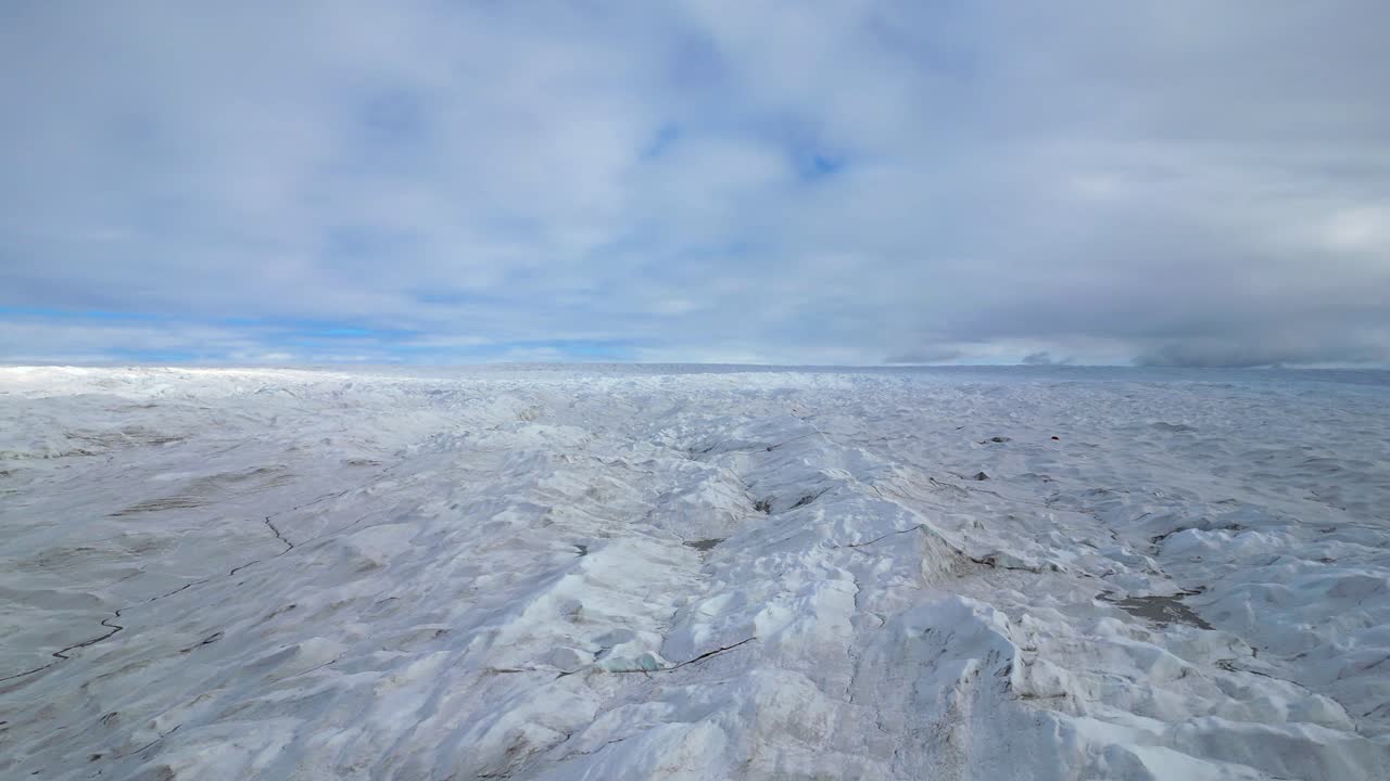 Aerial flyover: Vast textured ice glacier extends to distant horizon