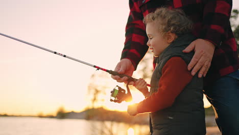 happy little boy is fishing and laughing resting with father or grandfather in nature in summer