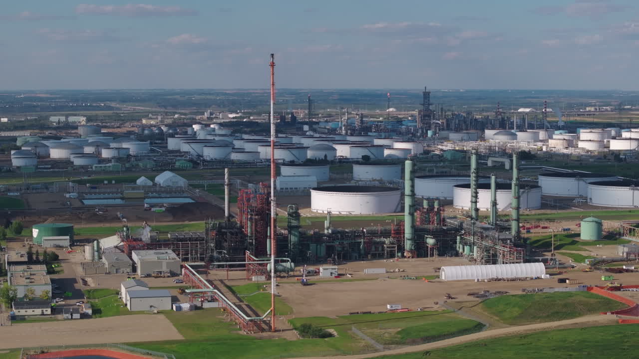 Aerial view of large oil refinery under clear blue sky with storage tanks visible