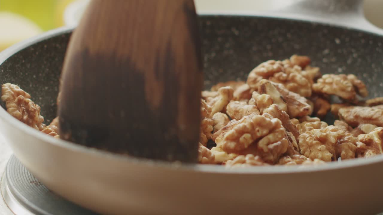 Una persona che tosta noci in padella in cucina