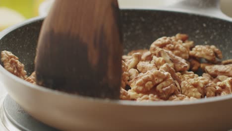 anonymous person frying walnuts in pan in kitchen