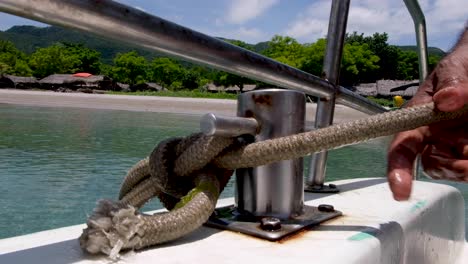 persons hand pulling anchor rope free on a boat on a tropical island in timor leste