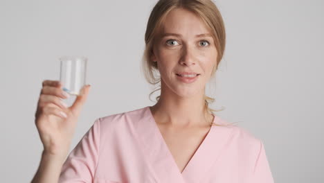 caucasian female doctor holding flask with pills.