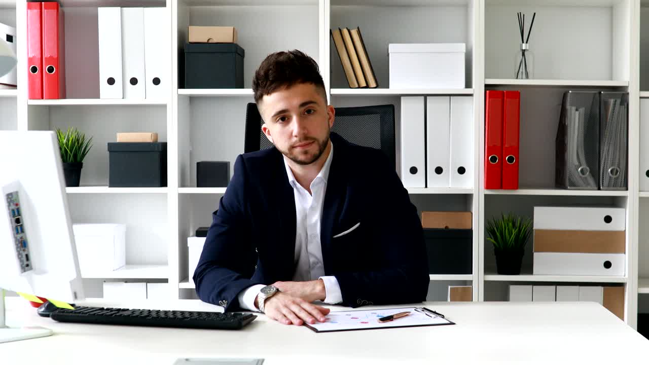 Junger Geschäftsmann kommt in einem modernen Büro am Arbeitsplatz an.