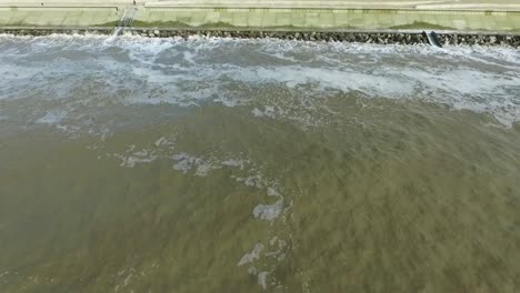 drone shot of the coastline, flying backwards while looking at sea defences and then the ocean. providing an aerial view of the coastal defences protecting the land