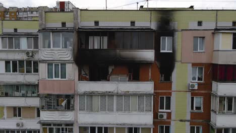 drone shot towards a sooty, burnt apartments and windows on a building, in a poor slum area of kyiv, cloudy day, in kiev, ukraine - dolly aerial view