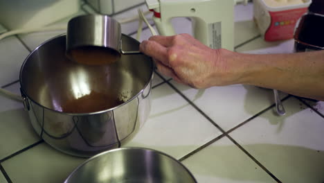 a chef scooping chocolate powder and flour into a metal mixing bowl as they make a vegan chocolate cake in the kitchen