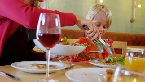 Mother-serving-salad-to-her-son-in-restaurant-4k