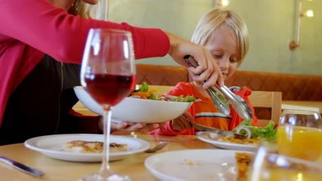 mother serving salad to her son in restaurant 4k