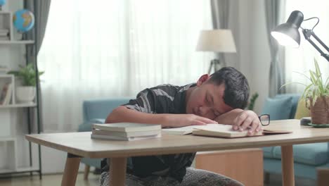 tired teenage boy sleeping on the table at home after doing home work