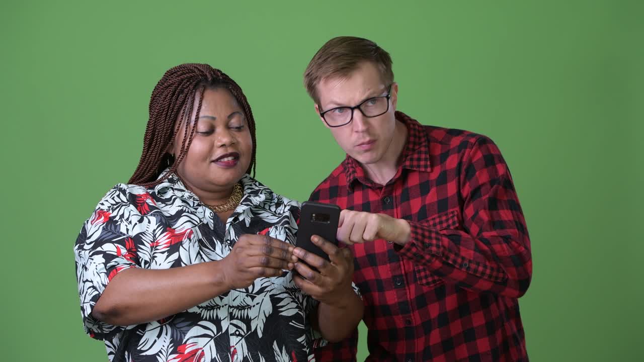 mujer africana con sobrepeso y un joven escandinavo juntos contra un fondo verde