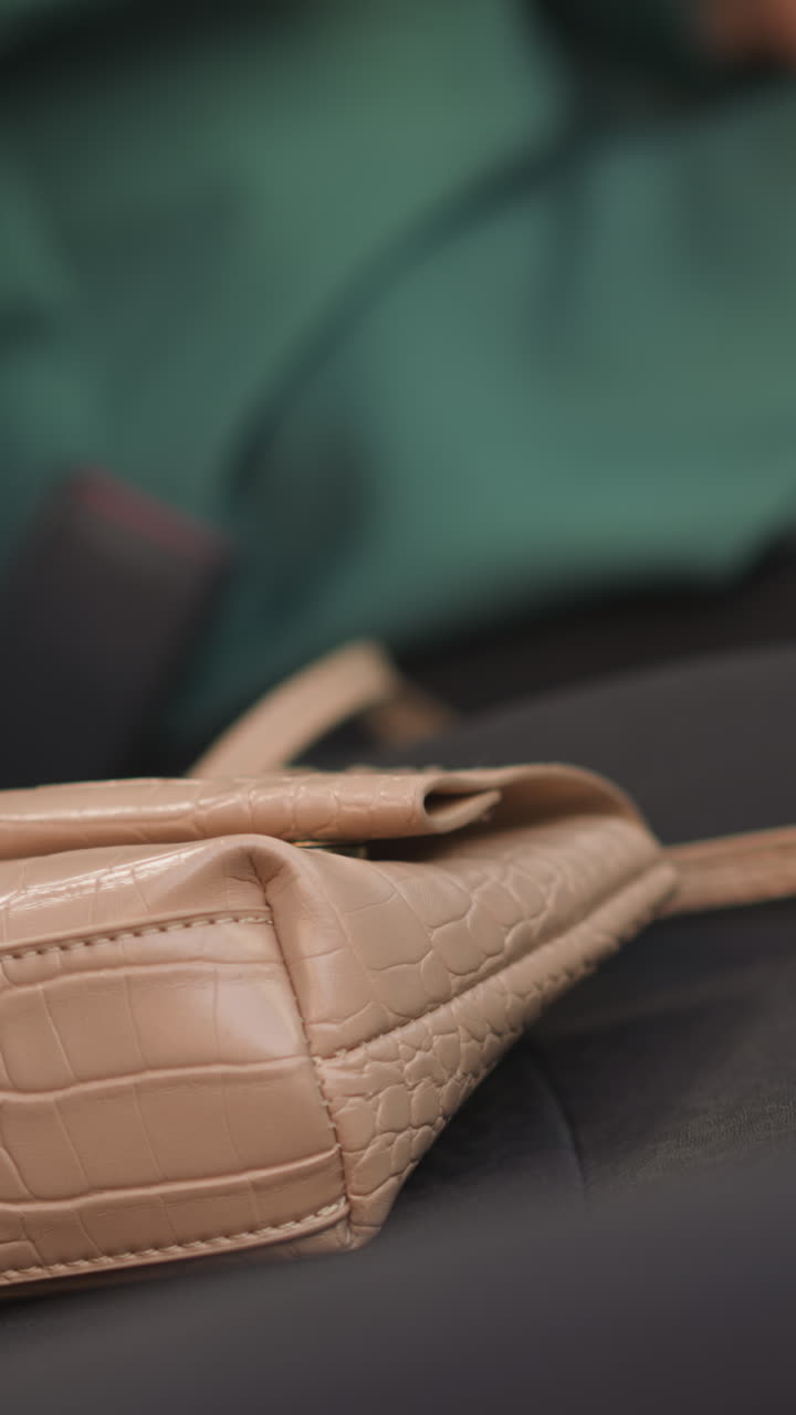 Angry woman throws smartphone on beige leather handbag lying on passenger seat in car. Businesswoman leaves device before starting engine following rules closeup