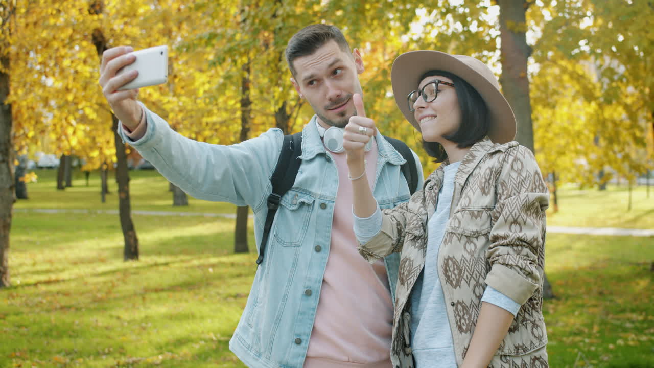 una pareja tomando una selfie en un parque de otoño