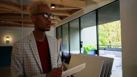 Front-view-of-young-black-businessman-writing-on-document-in-modern-office-4k