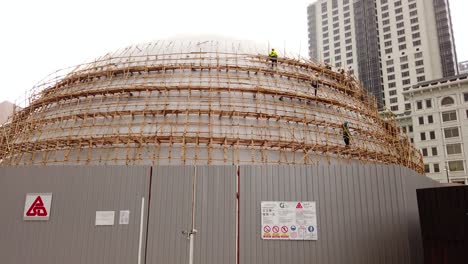 traditional bamboo scaffolding covering an oval structure in downtown hong kong