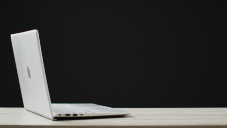 Video-of-white-laptop-on-table-with-copy-space-on-black-background