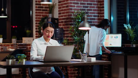 cheerful staff member looking over accounting figures on laptop screen at night